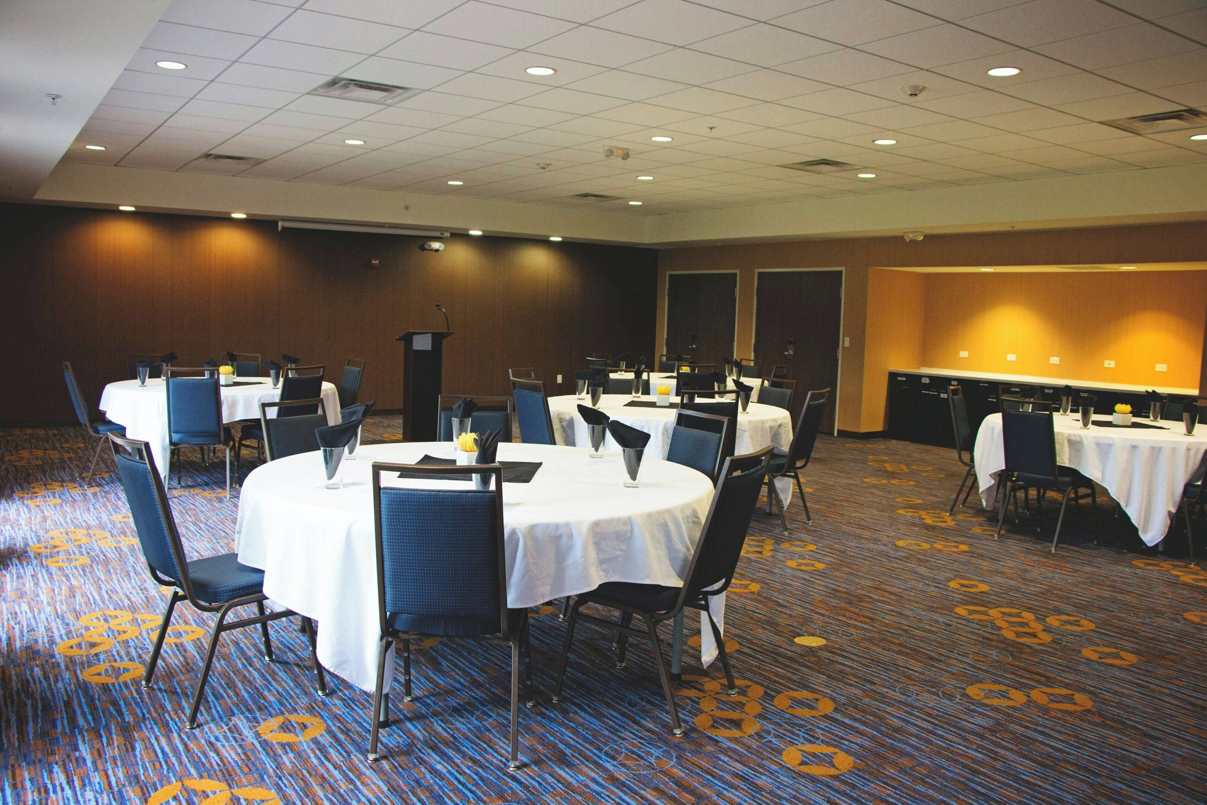 A conference room with round tables, chairs, and a podium.