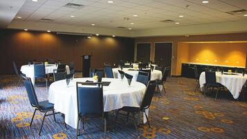A conference room with round tables, chairs, and a podium.