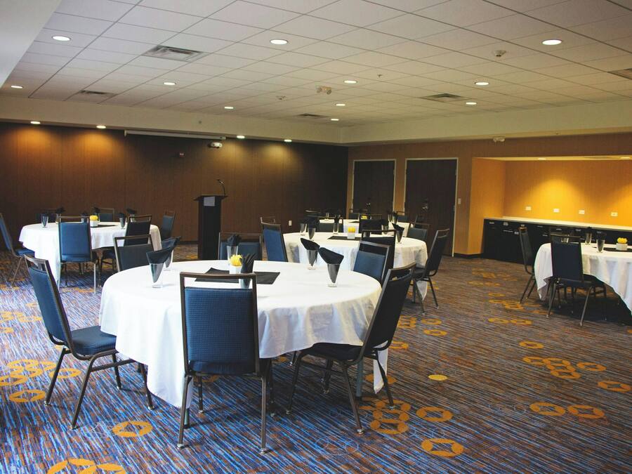 A conference room with round tables, chairs, and a podium.