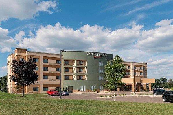 A Courtyard by Marriott hotel with a modern design, multiple floors, and a parking lot.