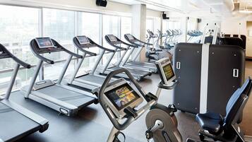 Une salle de sport équipée de tapis de course, de vélos d’appartement et d’autres appareils d’exercice.
