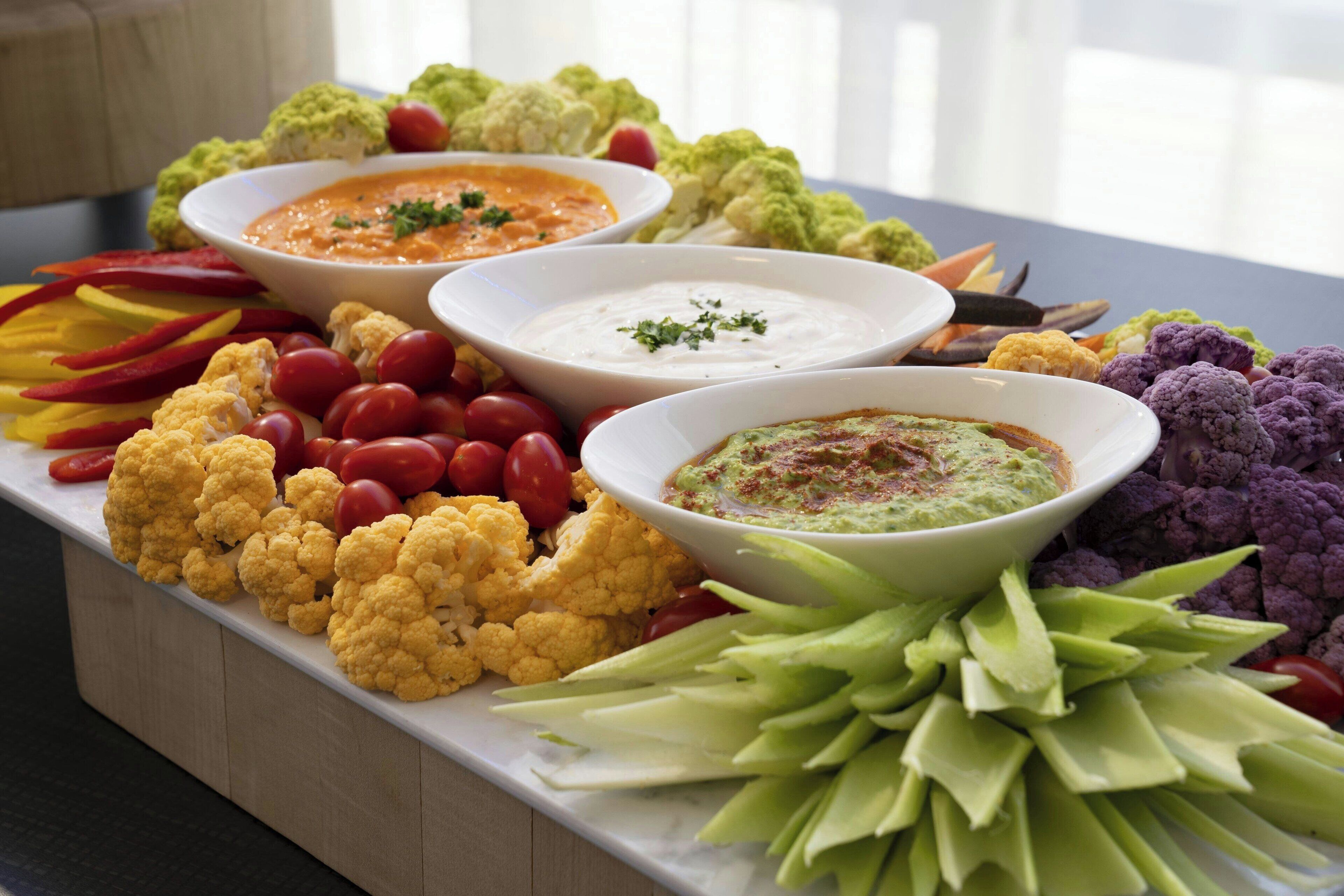 A tray of assorted vegetables and dips, including cauliflower, cherry tomatoes, and celery.