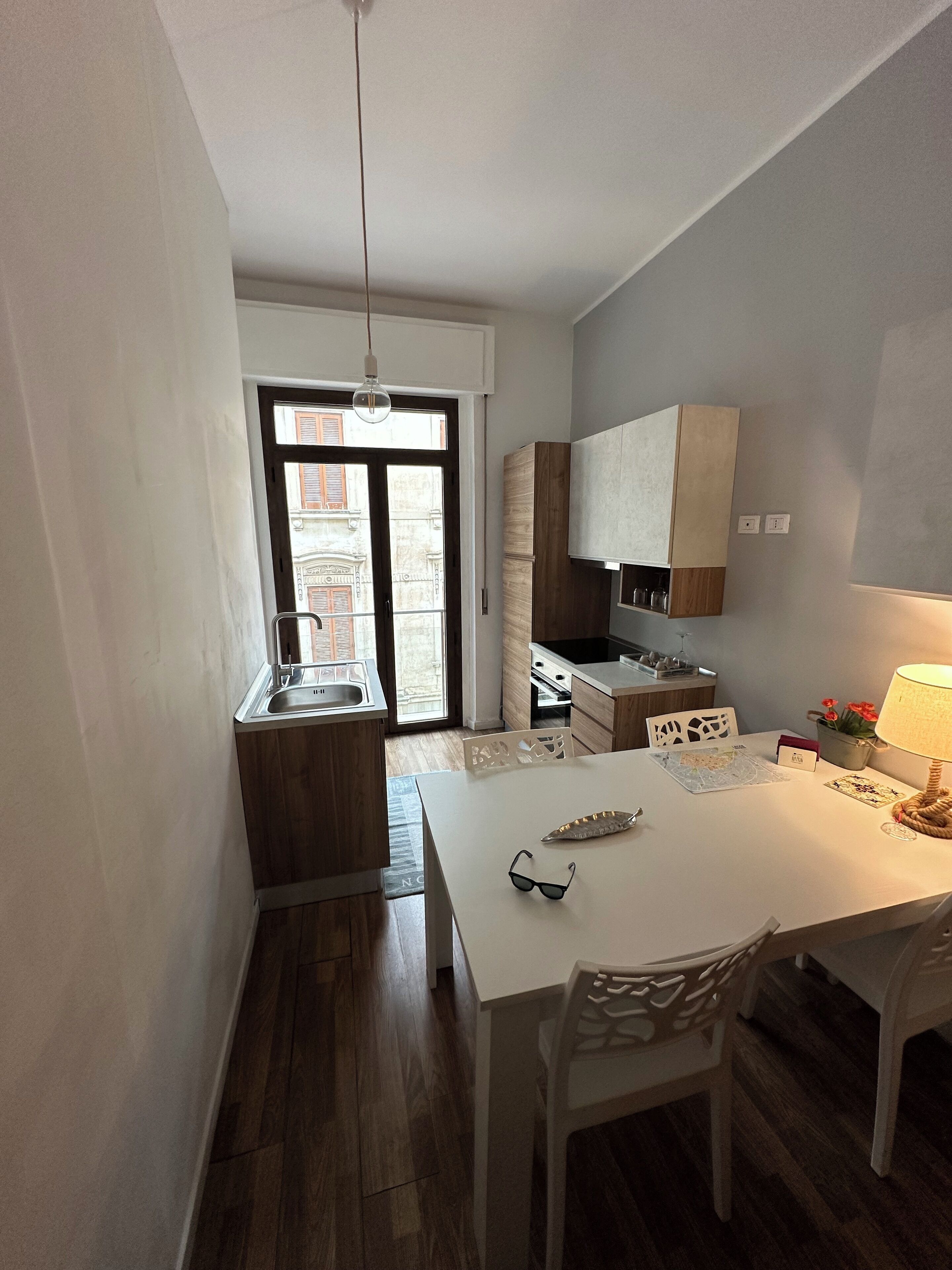 Een moderne keuken met houten kastjes, een wit aanrecht en een eethoek met tafel en stoelen.