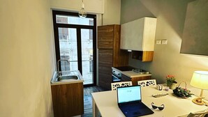 A compact kitchen with a dining area, a laptop on the table, and a view through the window. - B&B Degli Artisti (Lecce)