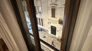 A view from a window overlooking a street with buildings, including one with a sign that reads "SCARDIA." - B&B Degli Artisti (Lecce)