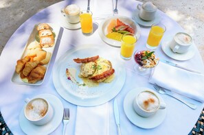 Ein Frühstückstisch mit Croissants, Eiern und Saft auf einer weißen Tischdecke.