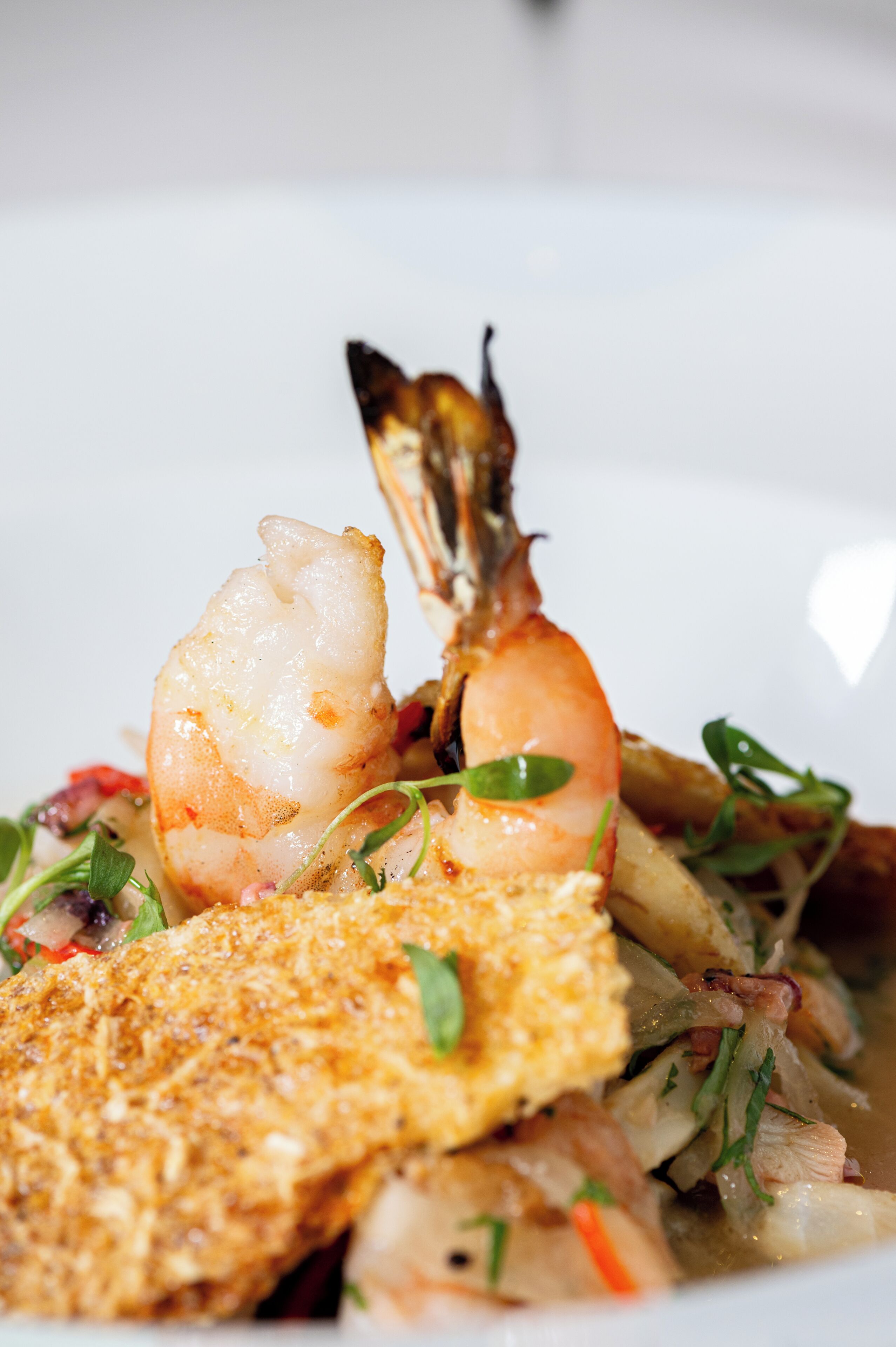 A seafood dish with shrimp and fish on a plate.