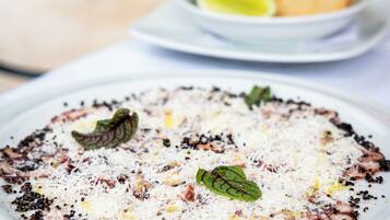 A plate of food with a white base, topped with black pepper, herbs, and cheese.