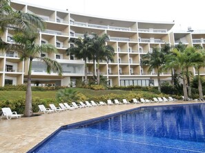 Una piscina al aire libre, sombrillas, sillones reclinables de piscina