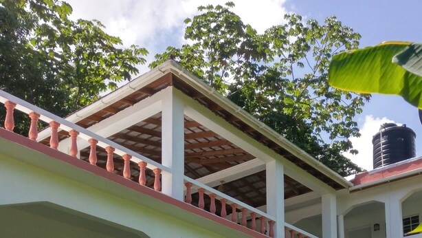 A two-story building with a white exterior, multiple balconies, and a white picket fence. - Polish Princess Guest House (Port Antonio)