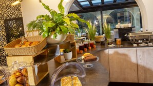 Un bufé de desayuno con diferentes alimentos y una planta grande en maceta.