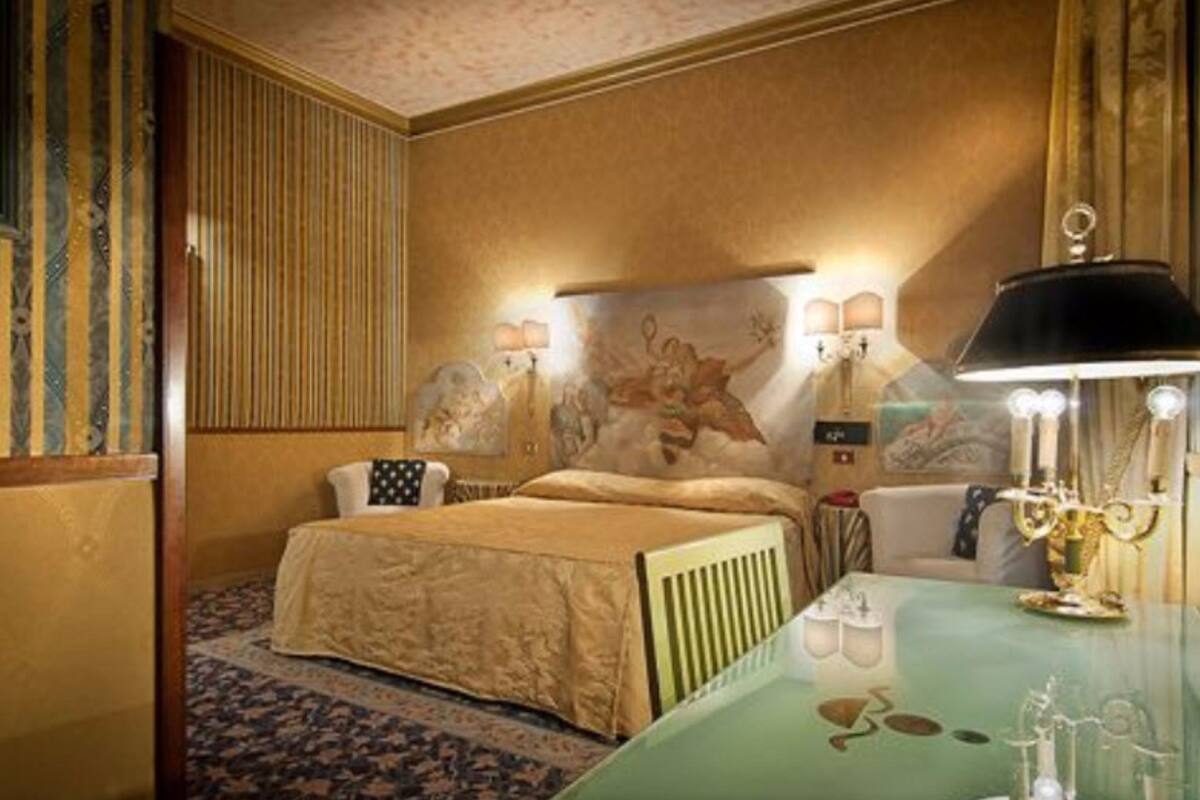 Ein Hotelzimmer mit einem Bett, einem Tisch mit einer Lampe und einer Wand mit einem dekorativen Gemälde.