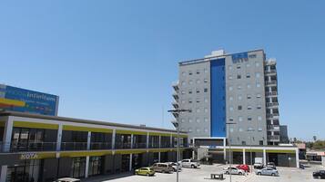 Un hotel de diseño moderno, con un llamativo esquema de colores azul y blanco, varios pisos y un estacionamiento con varios automóviles.