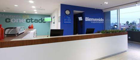 A reception desk with a blue wall, a clock, and a sign with tariff information.