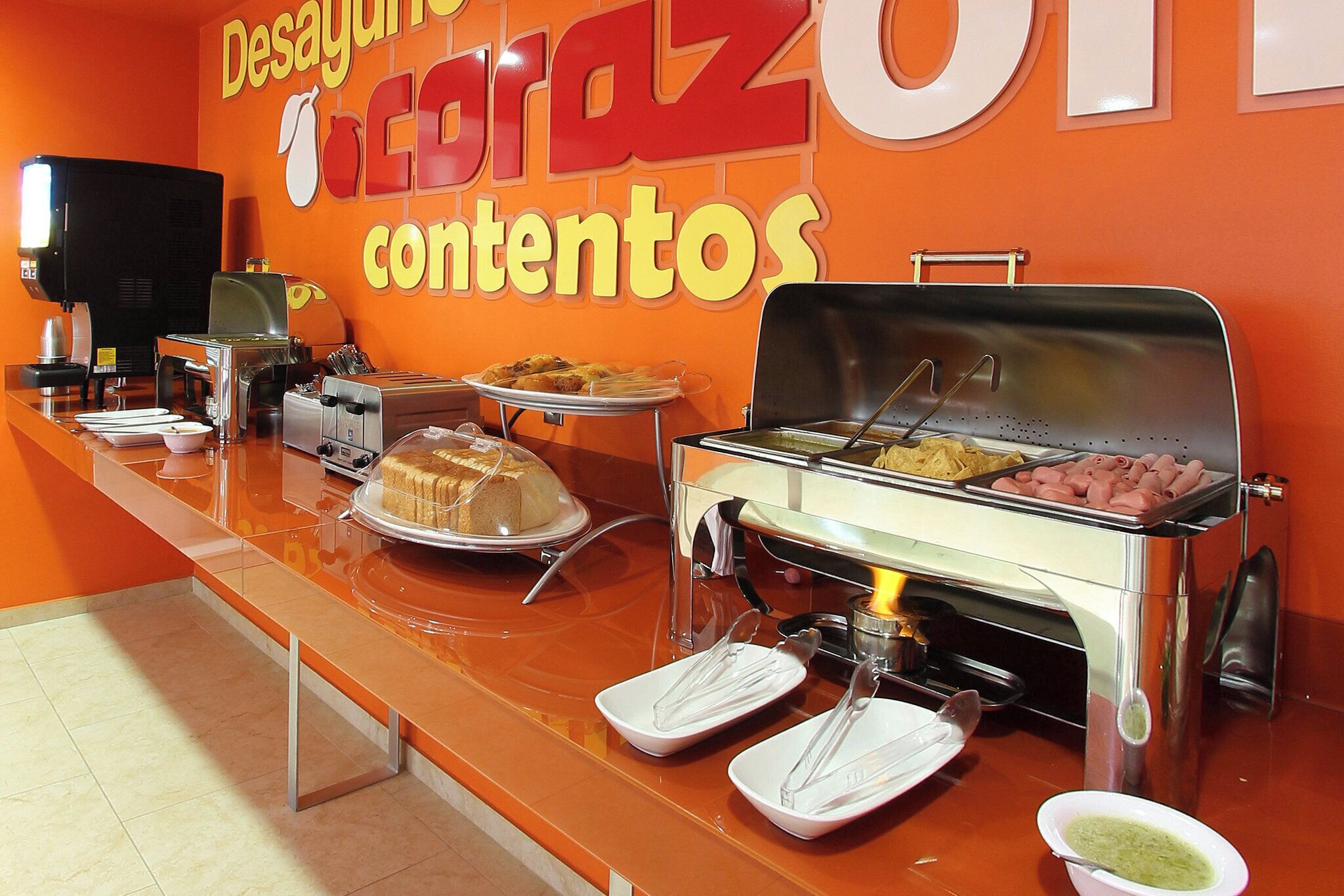 A buffet setup with various food items, a coffee machine, and a grill station.