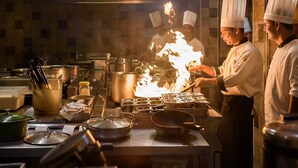 A professional kitchen with chefs performing a flambé. - Novotel Goa Resort & Spa Candolim (Candolim)