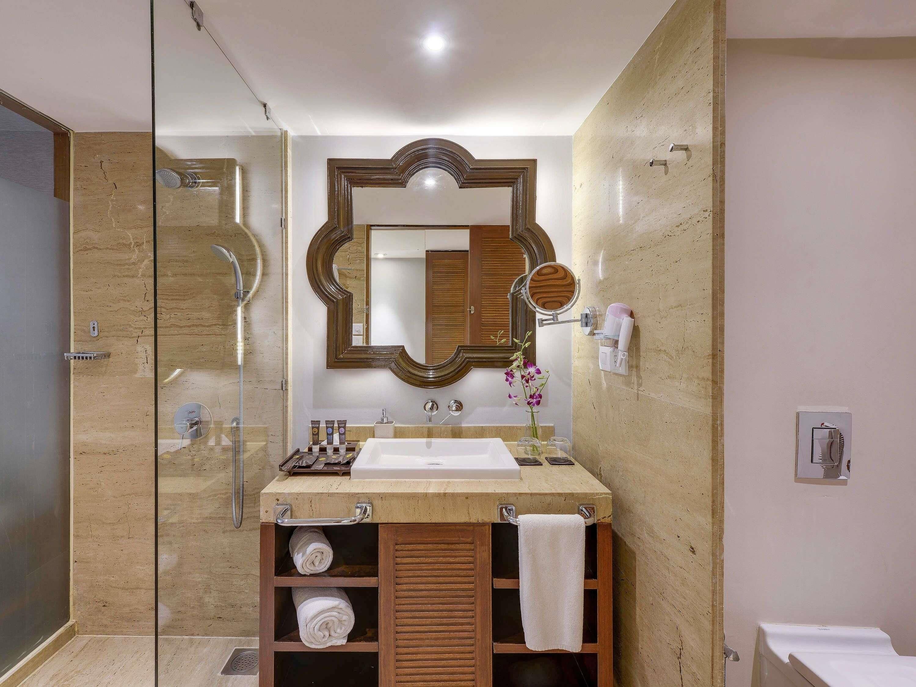 A bathroom with a glass shower enclosure, a wooden vanity with a mirror, and a towel rack.