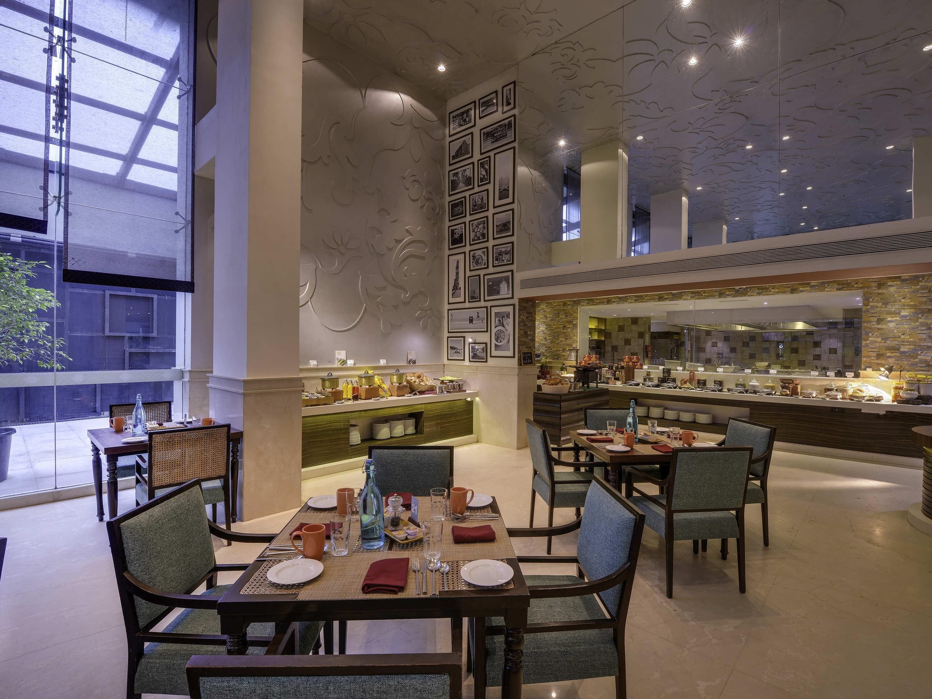 A spacious dining area with high ceilings and a modern design, featuring a central buffet and multiple seating arrangements.
