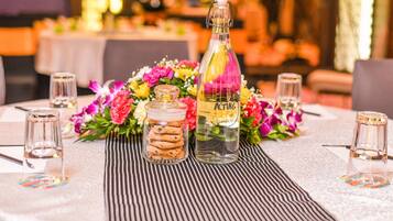 A table set with a glass bottle, a jar of cookies, and a floral arrangement.