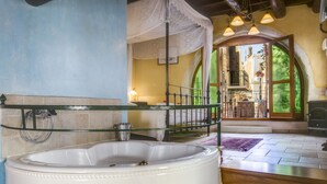 Un baño con una bañera independiente, cabina de ducha de vidrio y vistas a un balcón con mobiliario exterior.