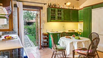 Une cuisine avec des meubles de rangement verts, une table à manger avec des chaises et un réfrigérateur.