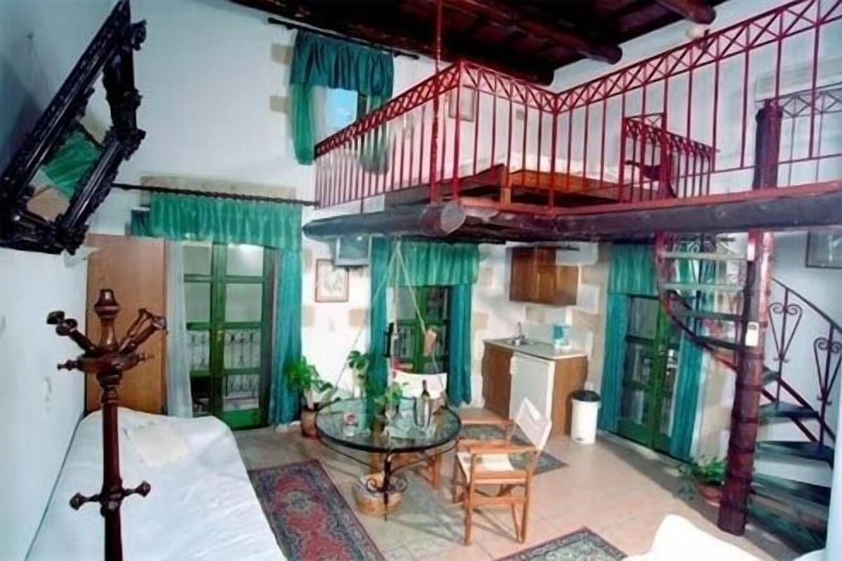 A spacious living area with a balcony, a round glass table, and a staircase.