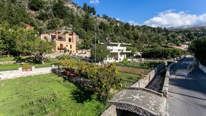 Un pueblo en una ladera con edificios de piedra, una calle pavimentada y un puente de piedra.
