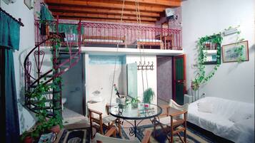 A compact living space with a dining area, a white sofa, and a spiral staircase leading to an upper level.