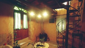 Un baño rústico con bañera, una puerta de madera, una mesa redonda con plantas y una escalera de caracol.