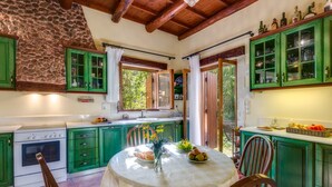 Una cocina con armarios verdes, una estufa blanca y una mesa de comedor con sillas.