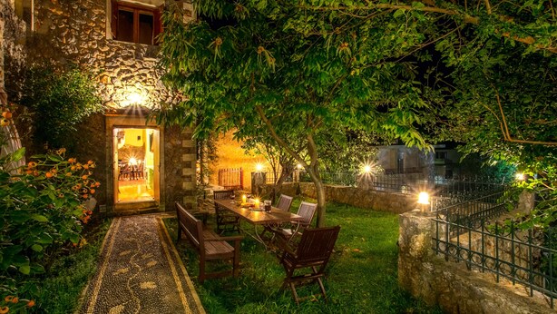 Un edificio de piedra con comedor, asientos al aire libre y un sendero jardín.
