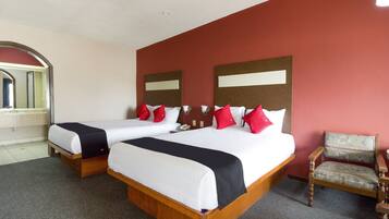 Habitación de hotel con dos camas, cabecero de madera, pared de acento roja y una sola silla.