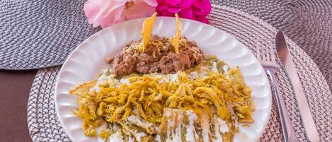 A plate of food with shredded chicken and a green sauce, placed on a woven placemat.