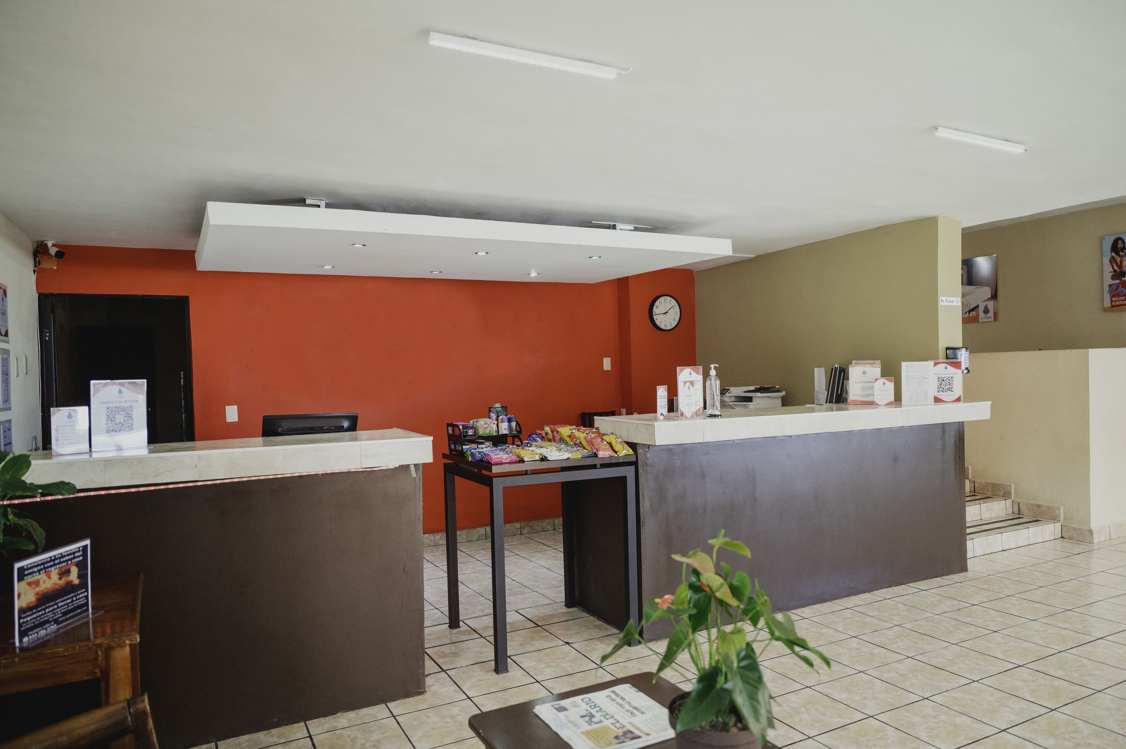 A reception area with a counter, a clock, and a table with snacks.