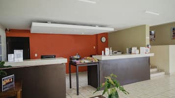 A reception area with a counter, a clock, and a table with snacks.