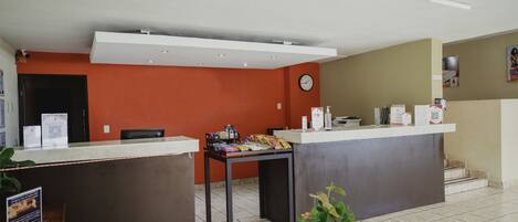 A reception area with a counter, a clock, and a table with snacks.