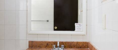 A bathroom with a marble sink, a mirror, and white tiled walls.