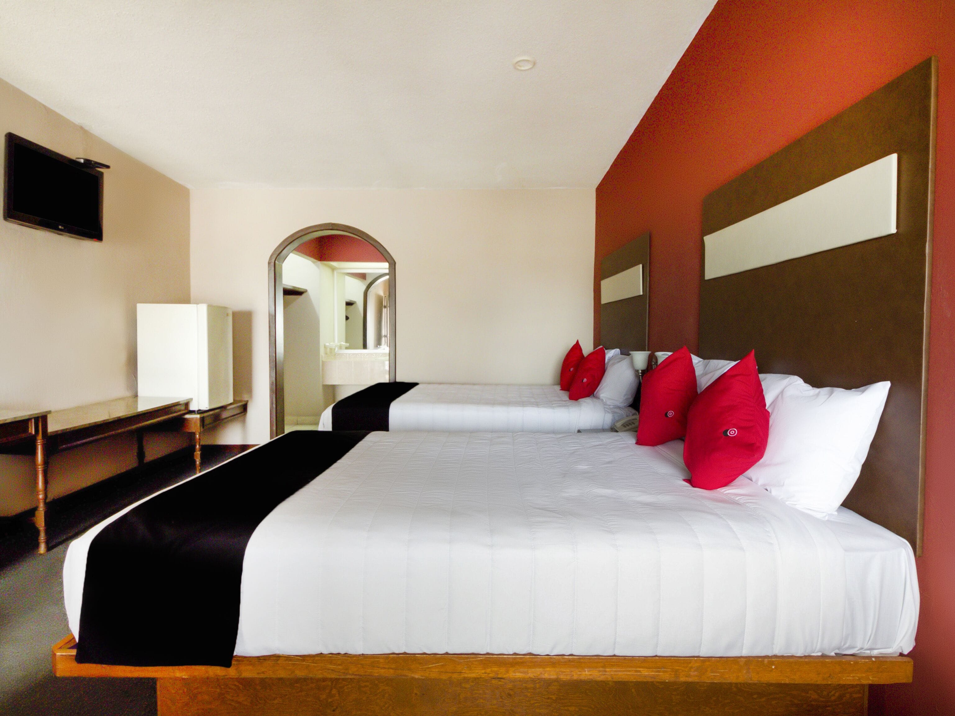 A hotel room with a large bed, a desk, a television, and a mirror.
