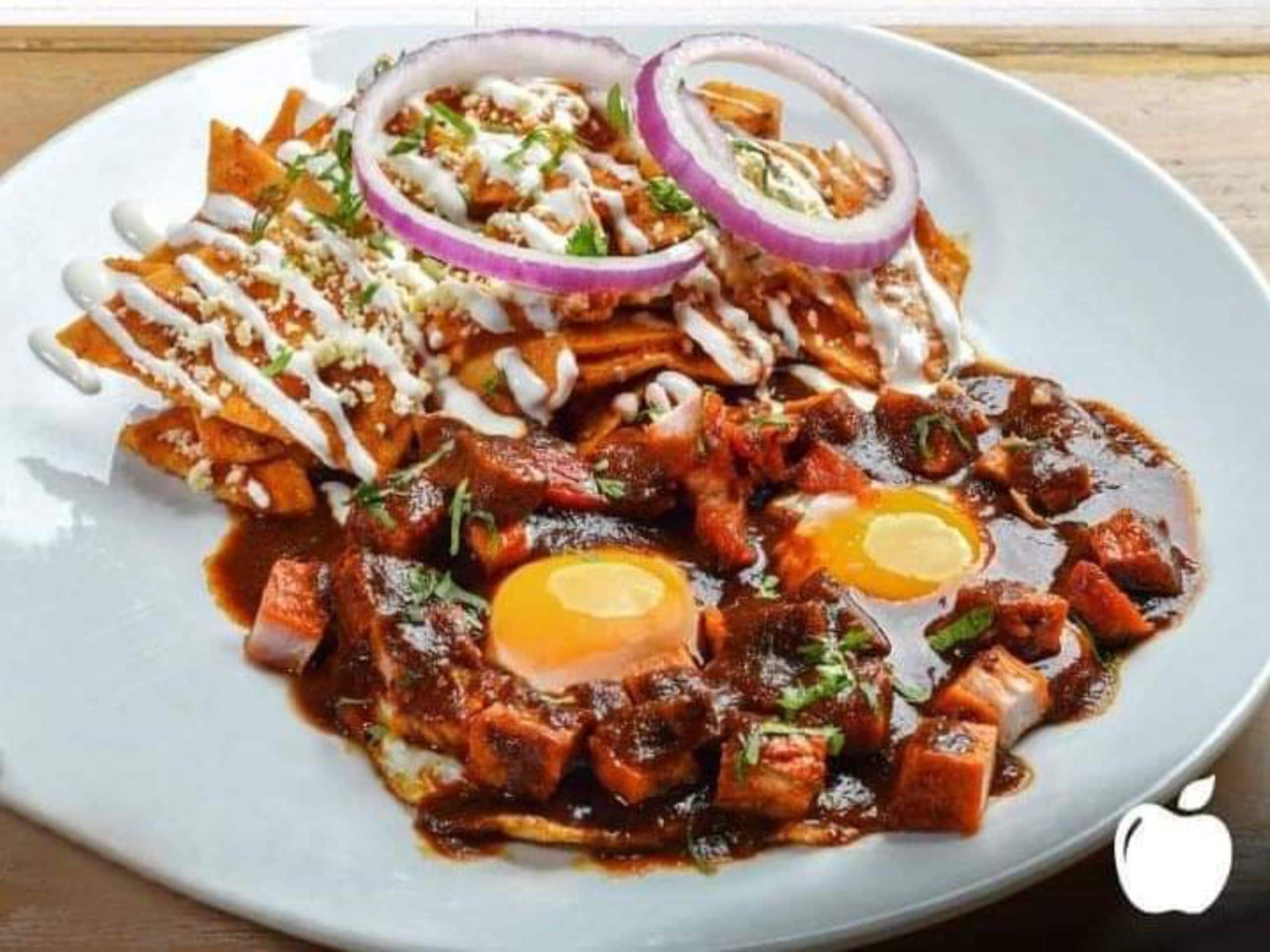 A plate of nachos topped with cheese, sour cream, and red onions.