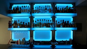 A bar with multiple shelves of liquor bottles and glasses.