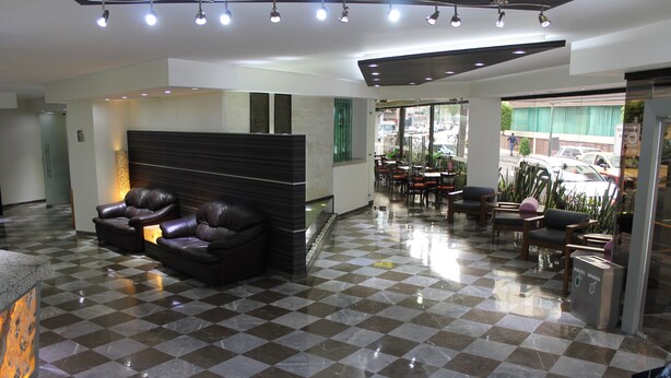 A hotel lobby with a checkered floor, leather seating, and a reception area.