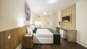 A hotel room with a bed, bedside table, TV, desk, and a small refrigerator. - Hotel Nacional Inn Curitiba Torres (Curitiba)