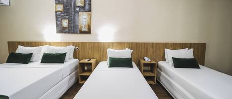 Habitación de hotel con dos camas individuales, cada una con ropa blanca y almohadas verdes, y un cuadro grande en la pared.