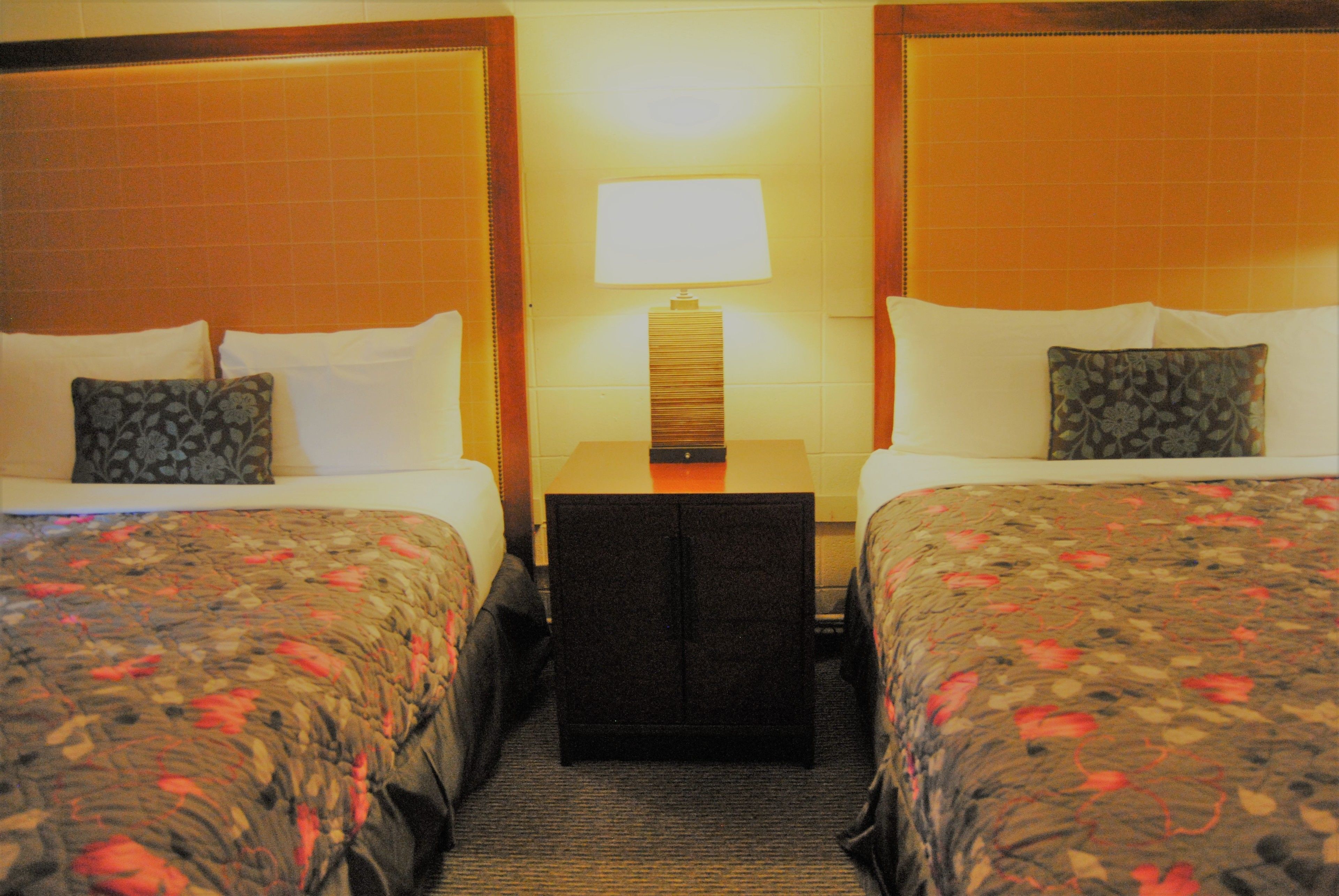 Une chambre d’hôtel avec deux lits, une table de chevet et une lampe.