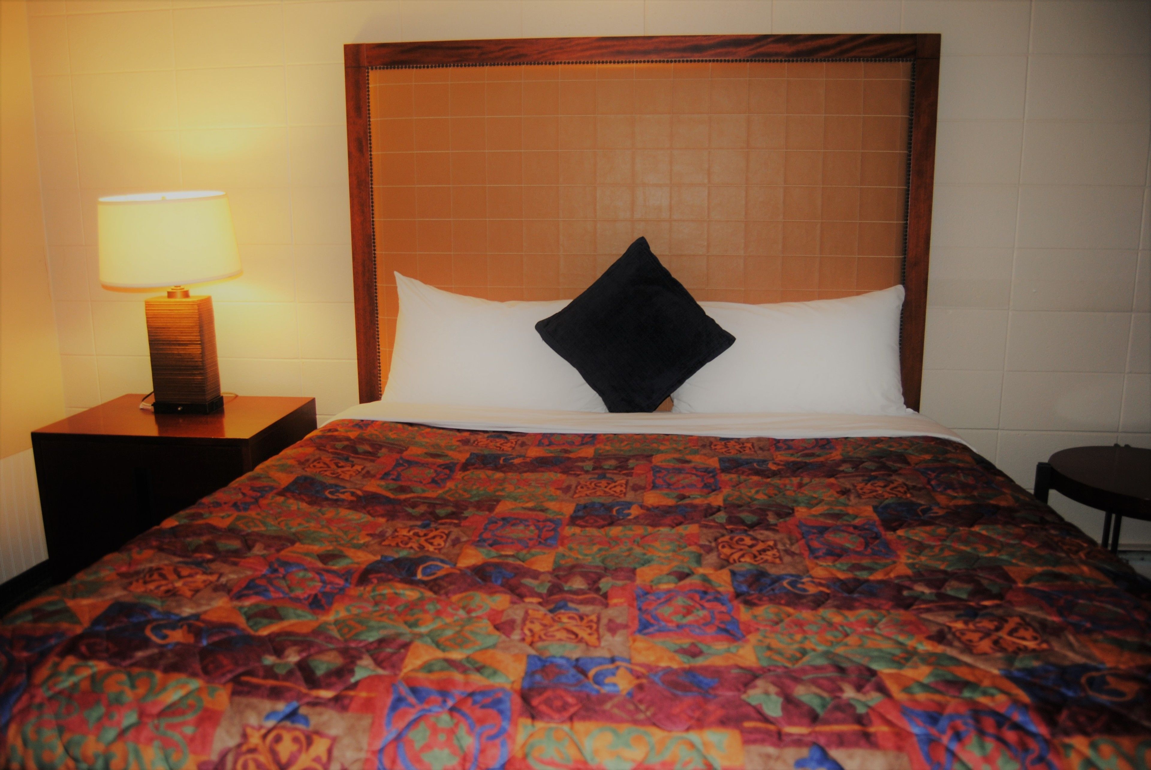 A hotel room with a large bed, a nightstand with a lamp, and a wooden headboard.