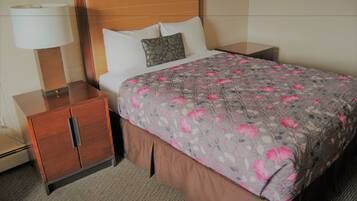 A hotel room with a bed, a nightstand, a wooden cabinet, and a lamp.