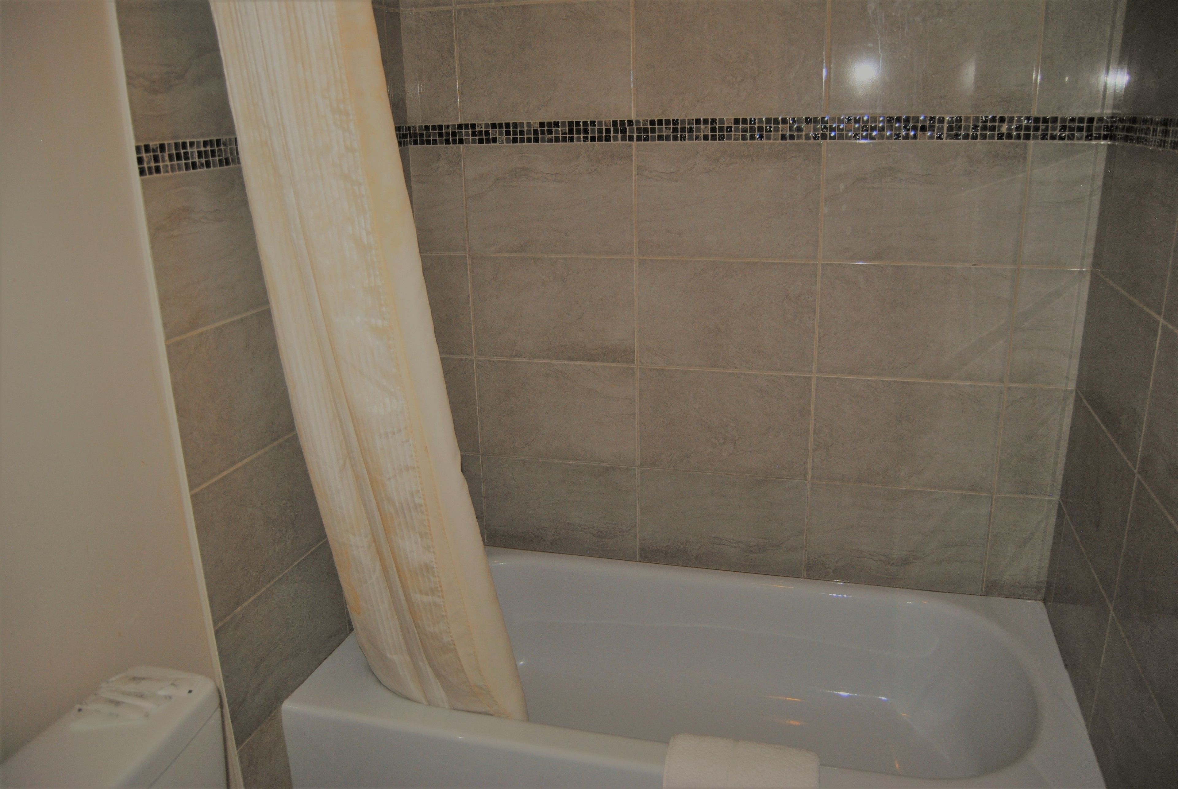 A bathroom with a bathtub, tiled walls, and a shower curtain.