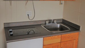 Une cuisine de taille réduite, dotée de meubles en bois, d’un four à micro-ondes, d’un évier et d’une cuisinière.