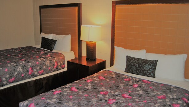 Une chambre d’hôtel avec deux lits, chacun recouvert d’une couvre-lit à motifs floraux, et comprenant une lampe de chevet et une table de nuit.