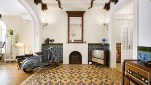 A room with a patterned floor, a vintage scooter, a fireplace, and a retro television. - Numa Barcelona Roca (Barcelona)